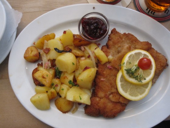 “Schnitzel Wiener Art” (pork meat) with cranberries, fried potatoes and salad