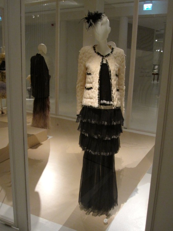 Chanel, Haute Couture Autumn-Winter 2004-2005; Ensemble consisting of a tweed vest with feathers embroidered in a braid, a long strapless dress with fine mousseline shoulder straps and a sur-jupe in silk pleaded mousseline decorated with ruche feathers. Comma-formed cap with feathers and a mousseline flower.